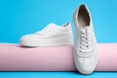 Photo of Stylish white shoes on light blue background