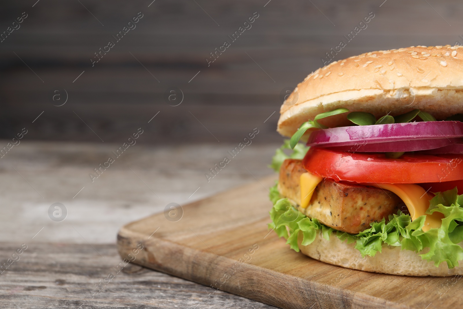 Photo of Delicious burger with tofu and fresh vegetables on wooden table, closeup. Space for text