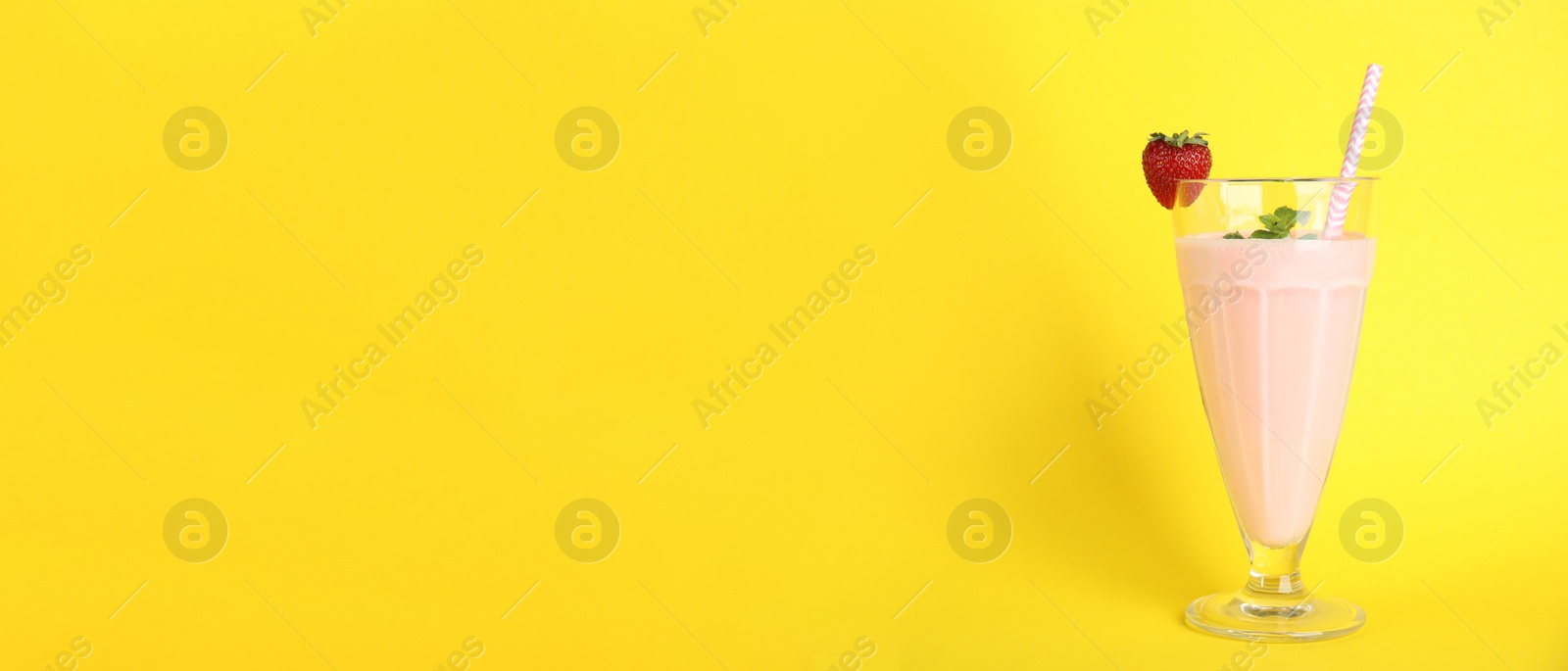 Photo of Tasty fresh milk shake with strawberry on yellow background. Space for text