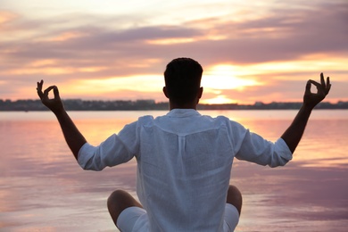 Photo of Man near river at sunset, back view. Nature healing power