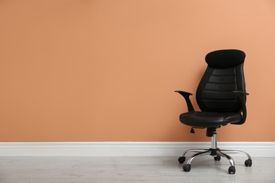 Photo of Modern office chair near orange coral wall indoors. Space for text