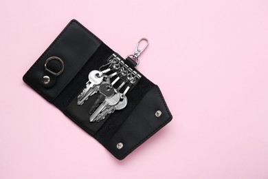Photo of Leather ring holder with keys on pink background, top view. Space for text
