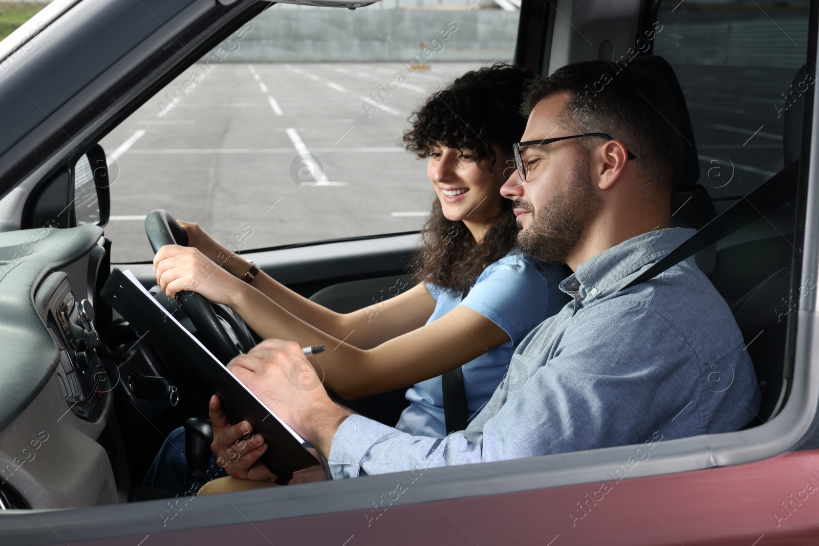 Photo of Driving school. Happy student passing driving test with examiner in car at parking lot