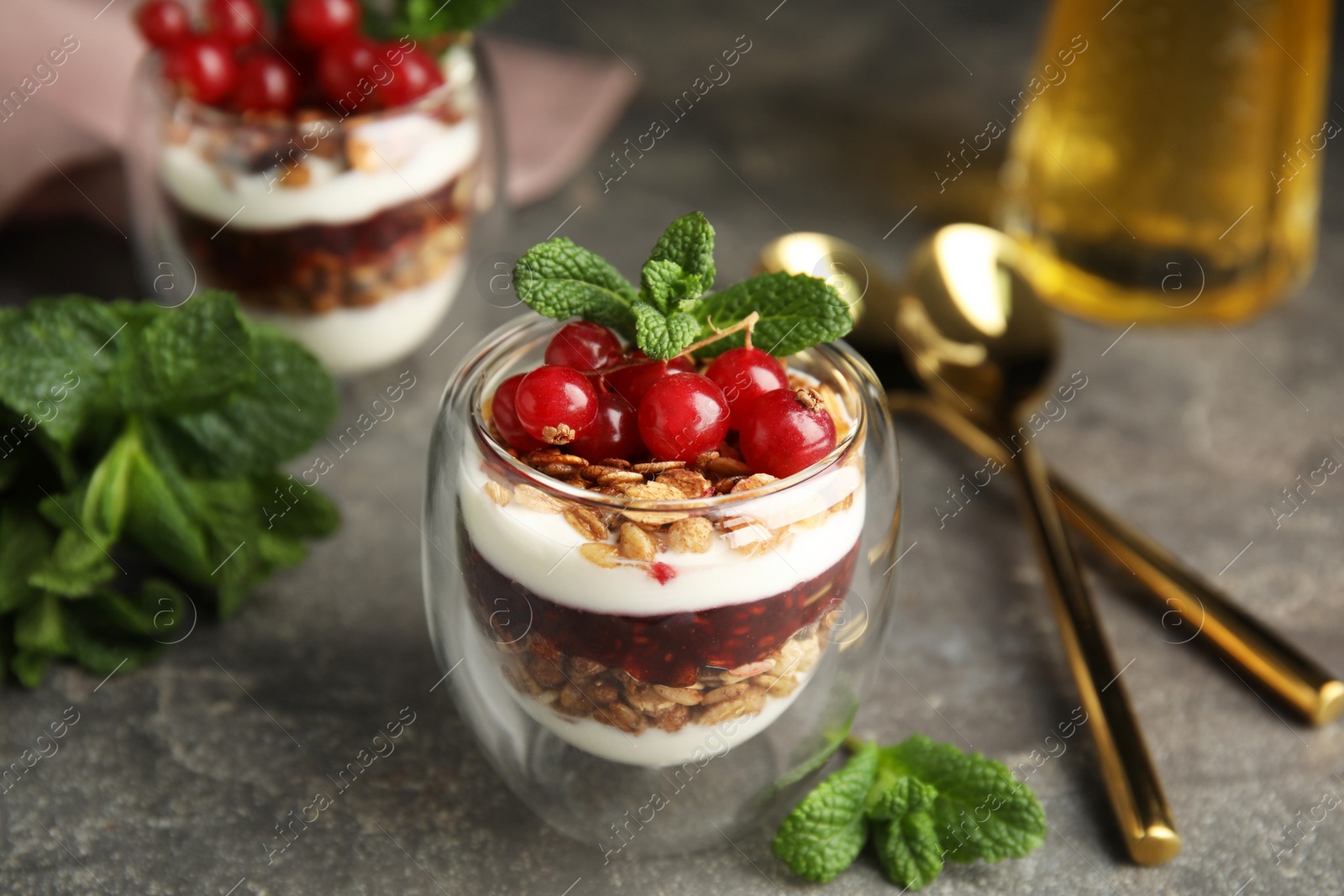 Photo of Delicious yogurt parfait with fresh red currants and mint on grey table, closeup