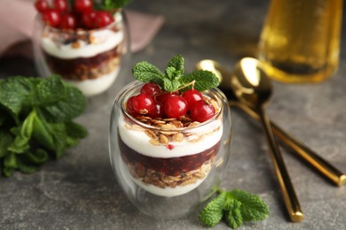 Photo of Delicious yogurt parfait with fresh red currants and mint on grey table, closeup