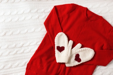 Red cashmere sweater and mittens on knitted plaid, top view