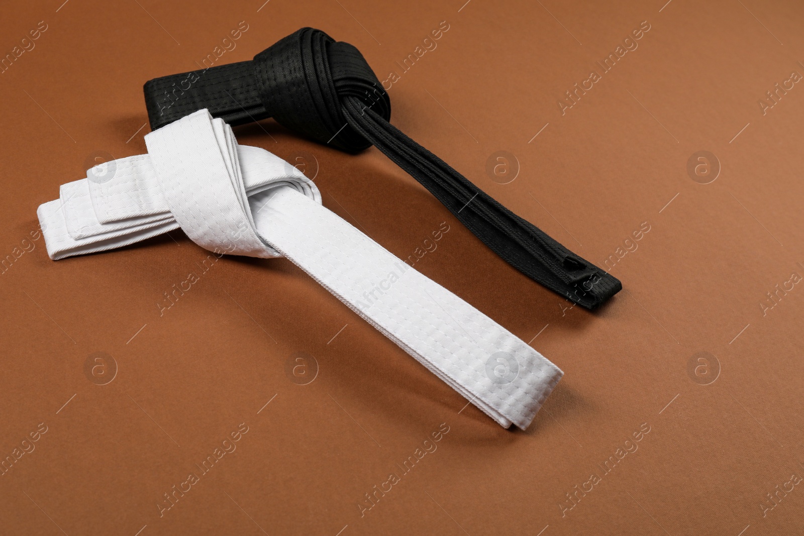 Photo of White and black karate belts on brown background