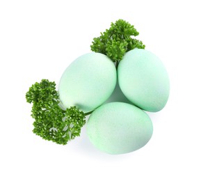 Photo of Turquoise Easter eggs painted with natural dye and curly parsley on white background, top view