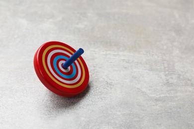 Photo of Bright spinning top on grey textured background, closeup. Space for text