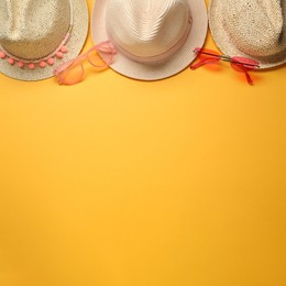 Photo of Hats and sunglasses on yellow background, flat lay with space for text. Sun protection accessories