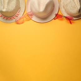 Hats and sunglasses on yellow background, flat lay with space for text. Sun protection accessories