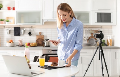 Food blogger taking photo of breakfast in kitchen