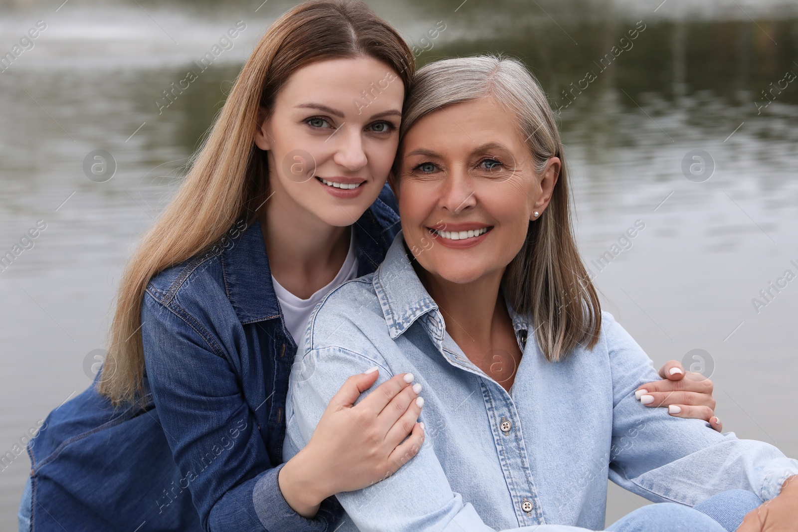 Photo of Happy mature mother and her daughter near pond