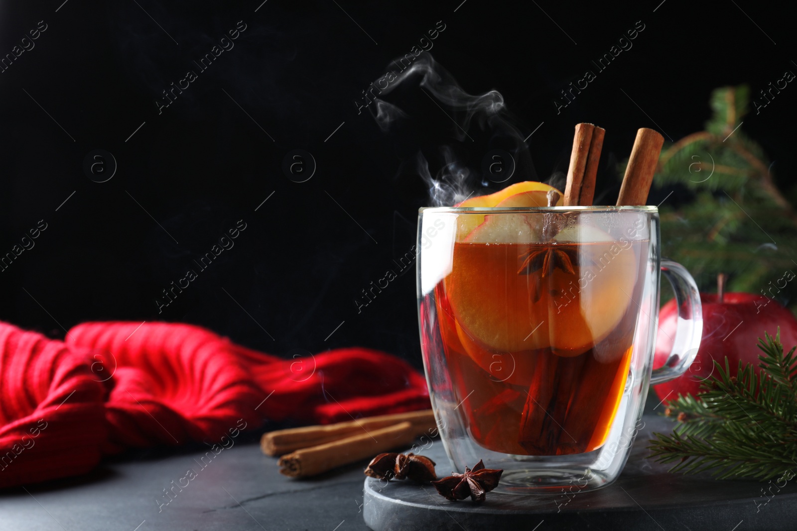 Photo of Aromatic hot mulled cider on black table. Space for text