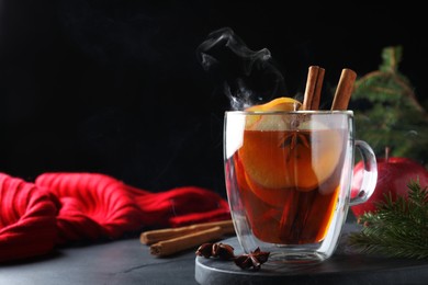 Aromatic hot mulled cider on black table. Space for text