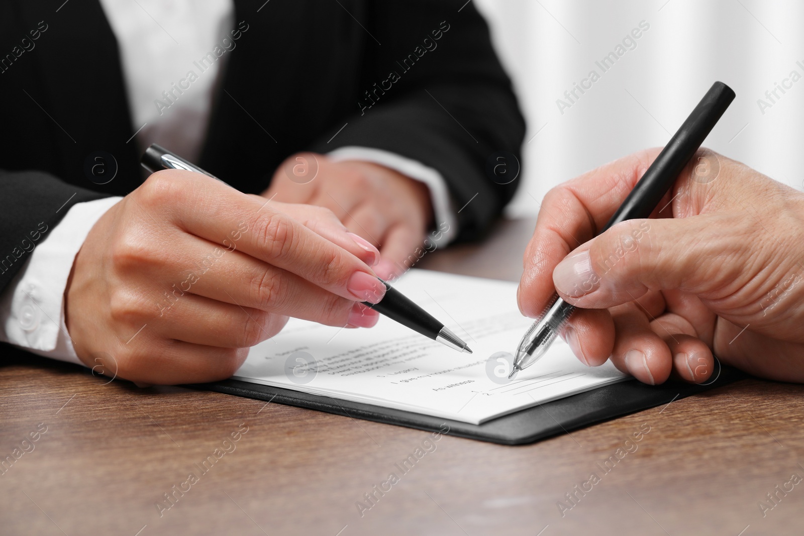 Photo of Manager showing client where he must to mark signature at wooden table indoors, closeup