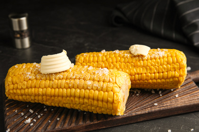 Delicious boiled corn with butter on wooden board