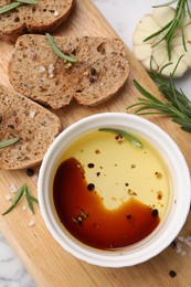 Photo of Bowl of organic balsamic vinegar with oil, bread slices and spices on white table, flat lay