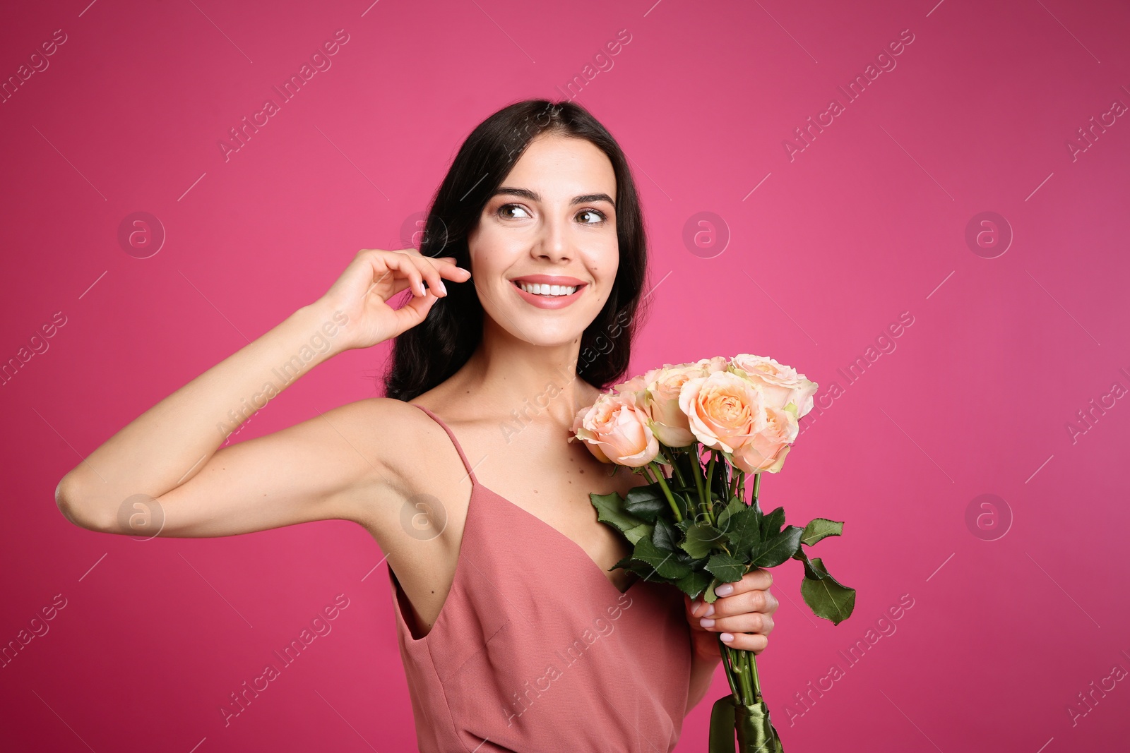 Photo of Portrait of smiling woman with beautiful bouquet on pink background