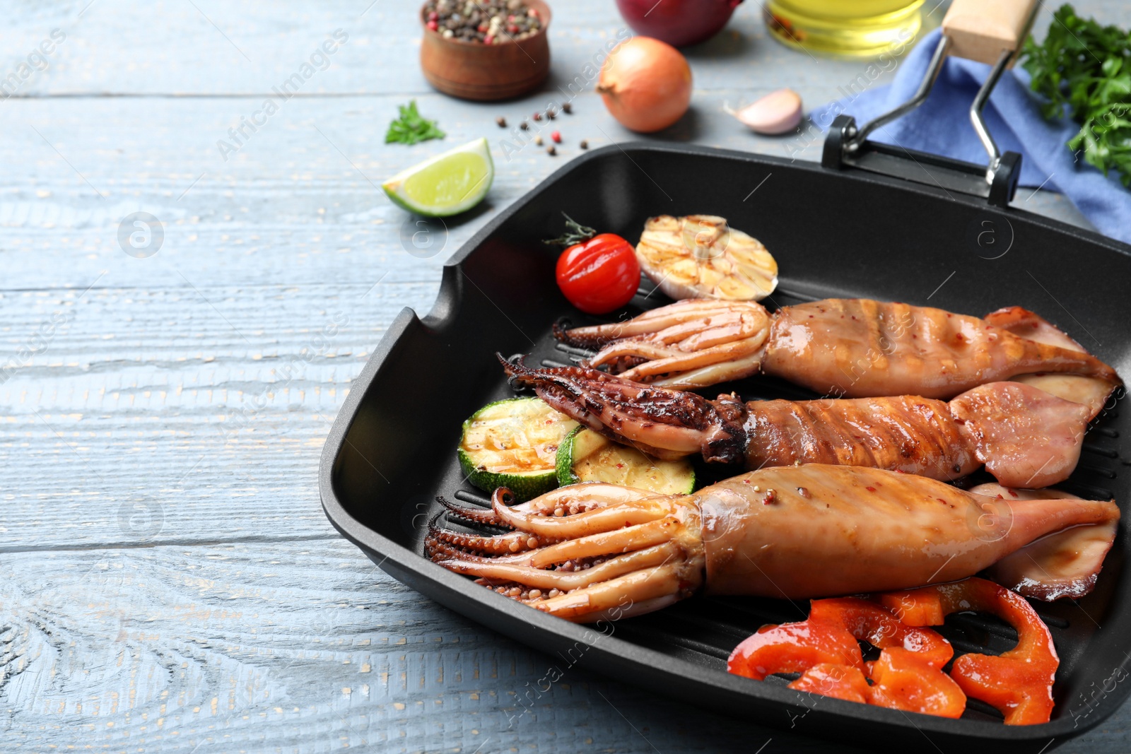 Photo of Tasty grilled squids with vegetables served on grey wooden table