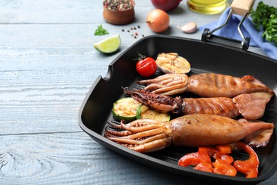 Tasty grilled squids with vegetables served on grey wooden table