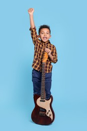 Photo of Cute African-American boy with electric guitar on turquoise background