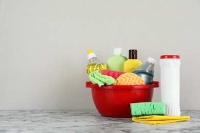 Photo of Red basin with cleaning products on marble table. Space for text