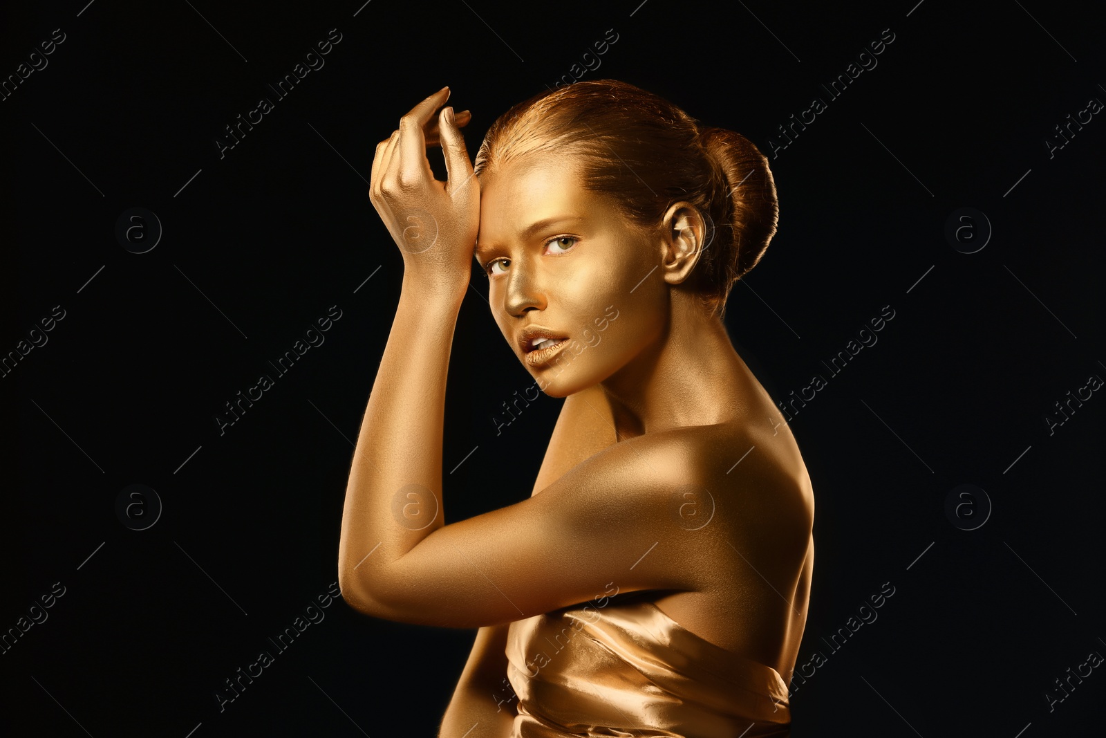 Photo of Portrait of beautiful lady with gold paint on skin against black background