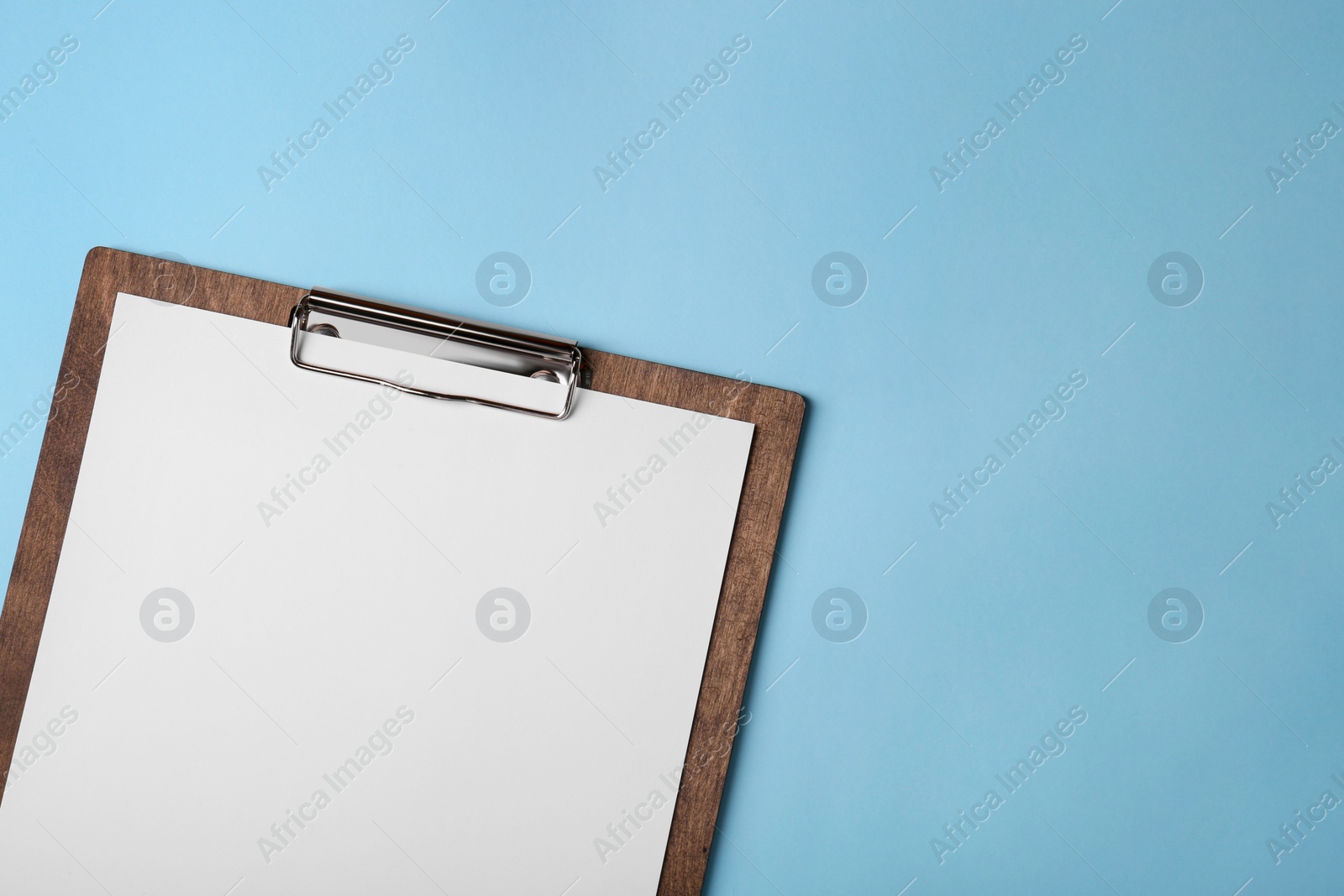 Photo of New wooden clipboard with sheet of blank paper on light blue background, top view. Space for text