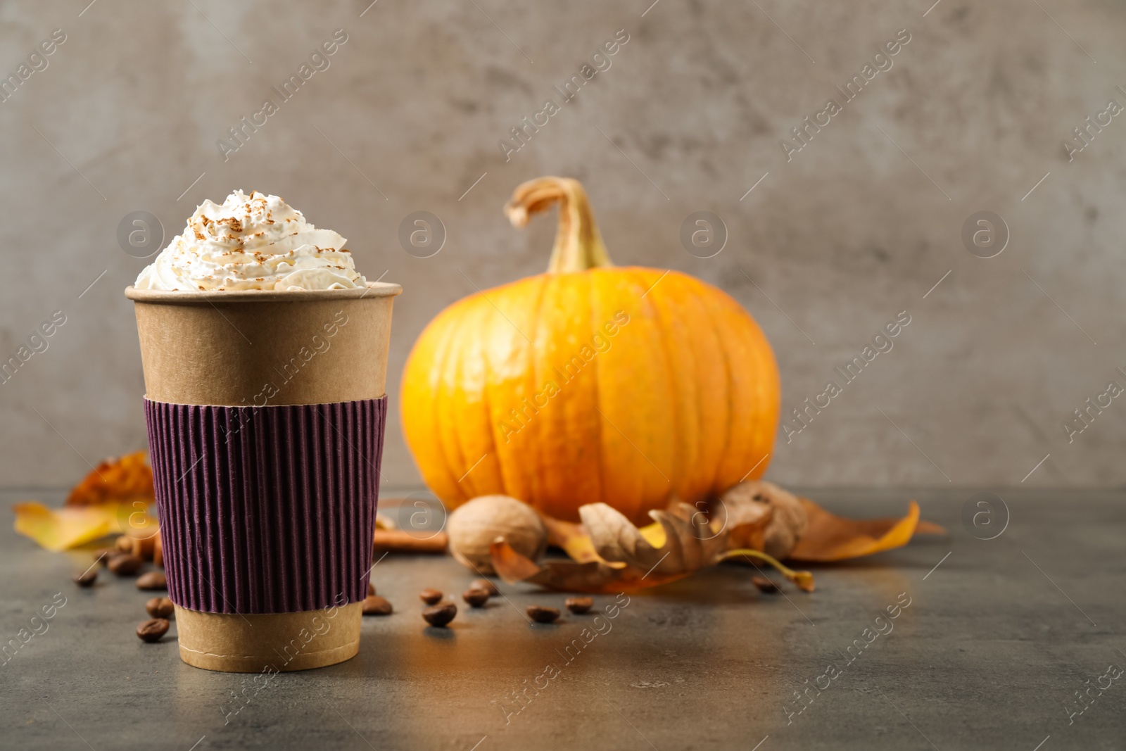 Photo of Paper cup with tasty pumpkin spice latte on grey table. Space for text