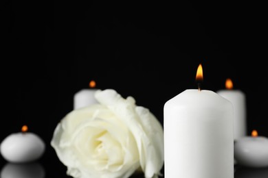 Photo of White rose and burning candle in darkness, closeup with space for text. Funeral symbols