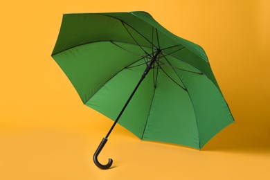 Photo of Stylish open green umbrella on yellow background