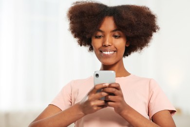 Photo of Smiling African American woman with smartphone at home