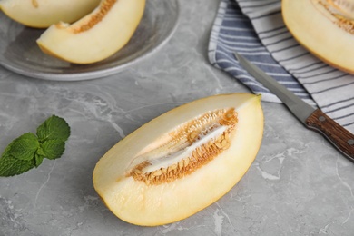 Photo of Tasty cut ripe melon on grey marble table