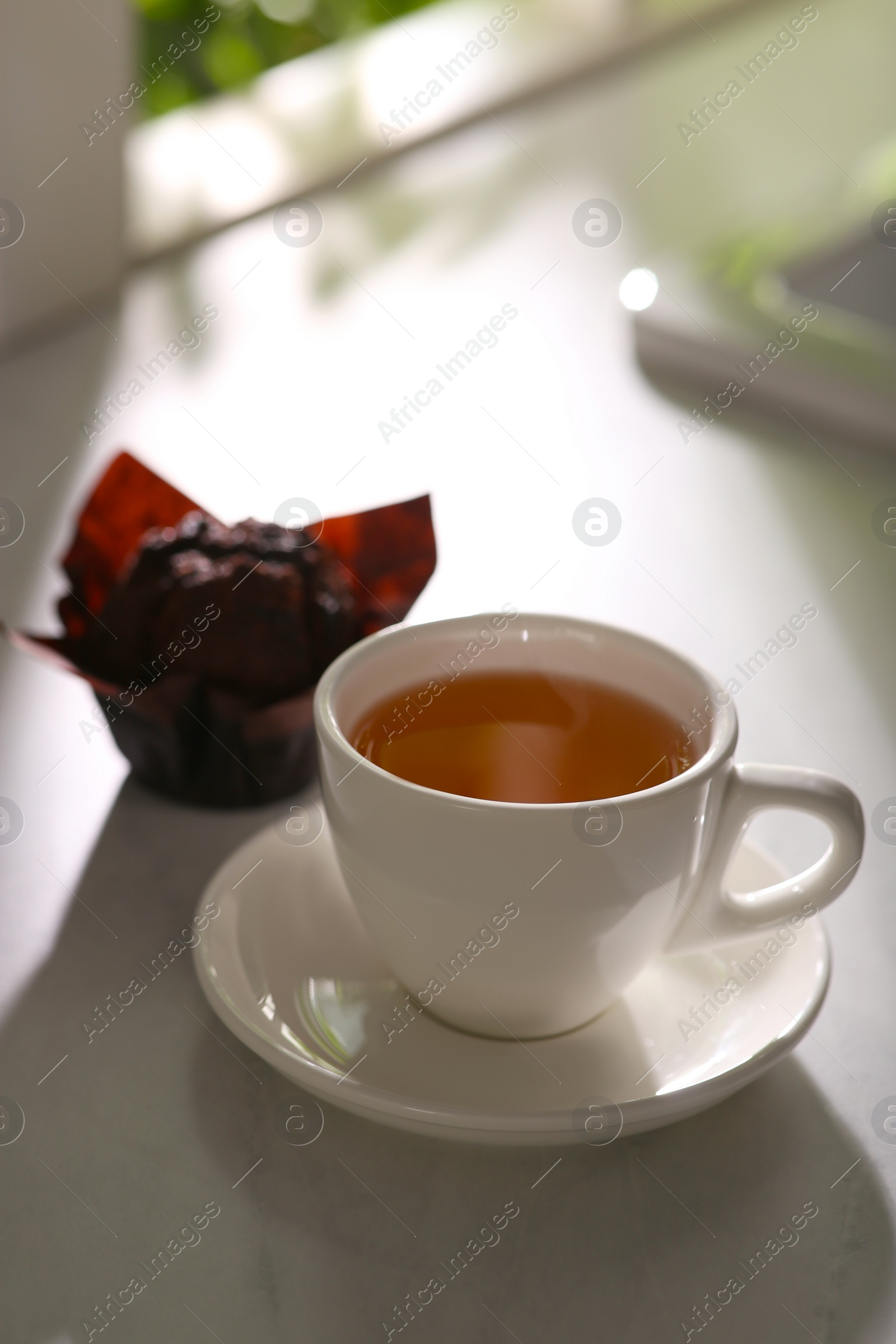 Photo of Delicious tea and cupcake on sunlit table. Good morning