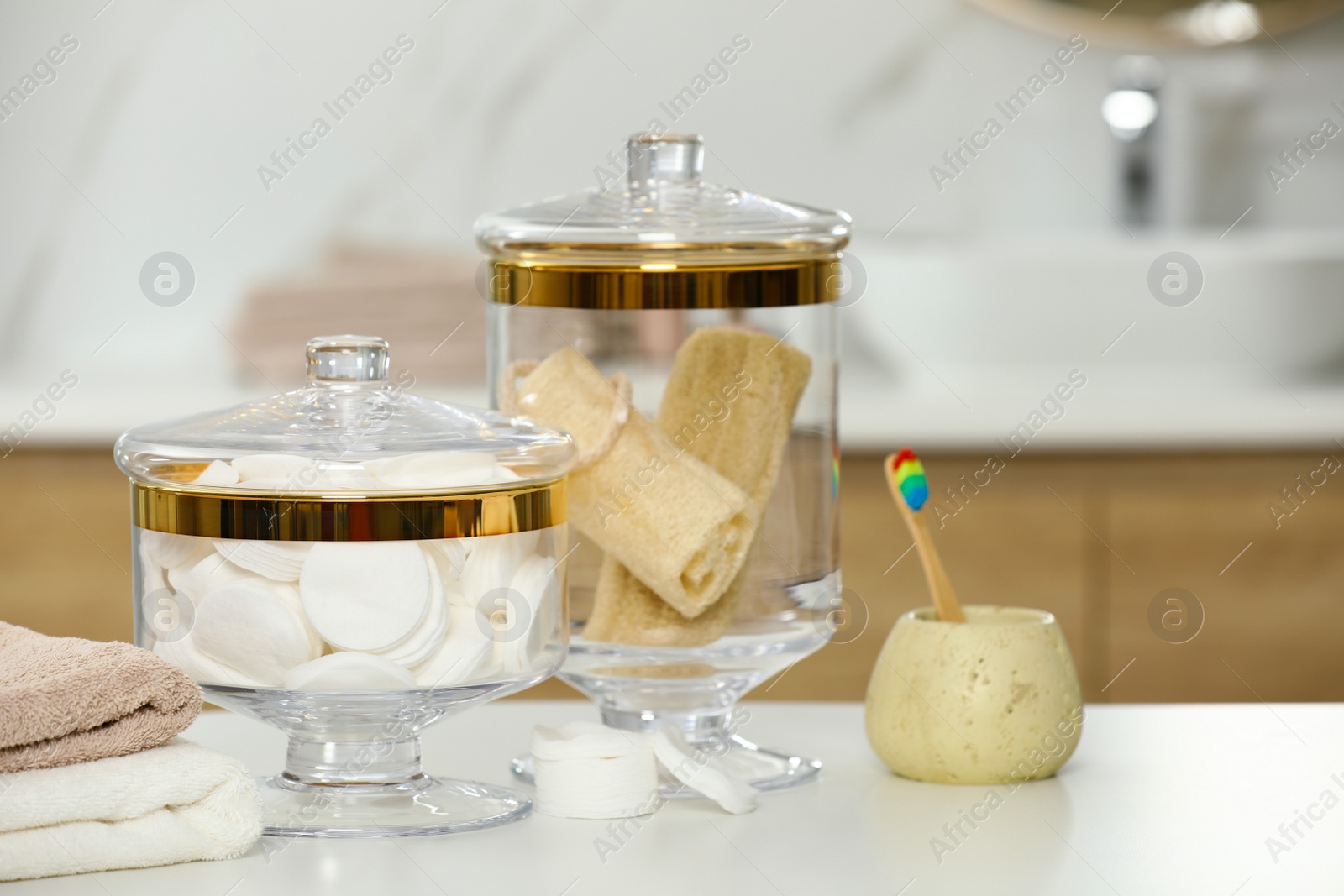 Photo of Composition of glass jar with cotton pads and luffa sponges on table in bathroom. Space for text