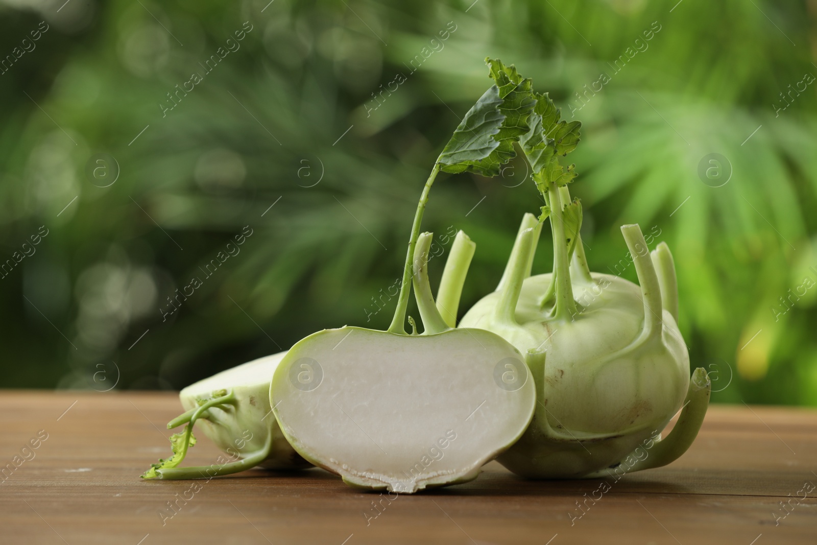 Photo of Whole and cut kohlrabi plants on wooden table