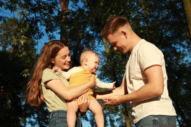 Photo of Parents with their cute daughter spending time together in park on summer day