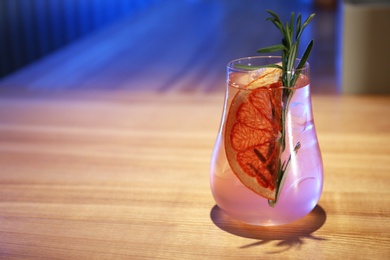 Glass of delicious cocktail with vodka on wooden counter in bar. Space for text