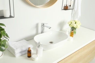 Photo of Bath accessories, sink and roses in bathroom