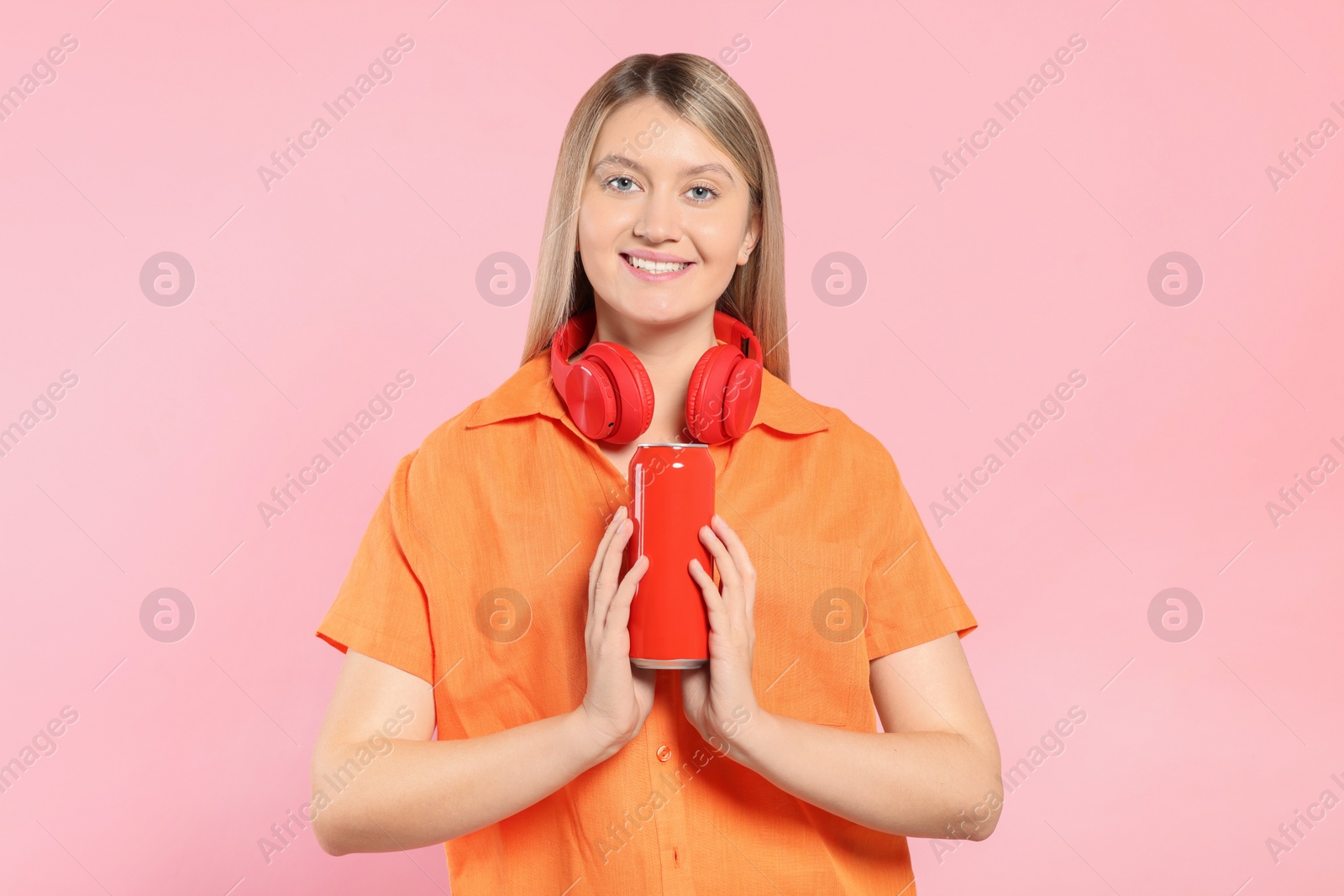 Photo of Beautiful happy woman holding red beverage can on pink background. Space for text