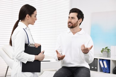 Doctor with clipboard consulting patient during appointment in clinic