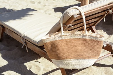 Photo of Straw bag on wooden sunbed outdoors. Beach accessory