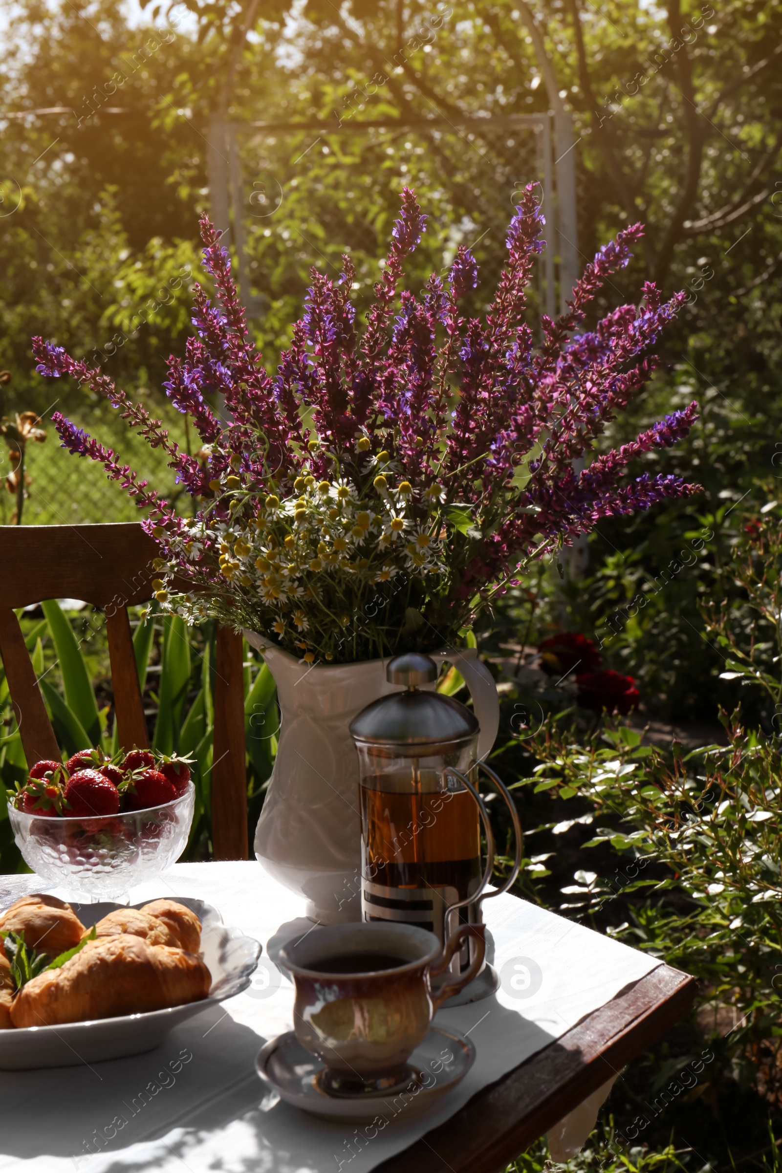 Photo of Beautiful bouquet of wildflowers on table served for tea drinking in garden