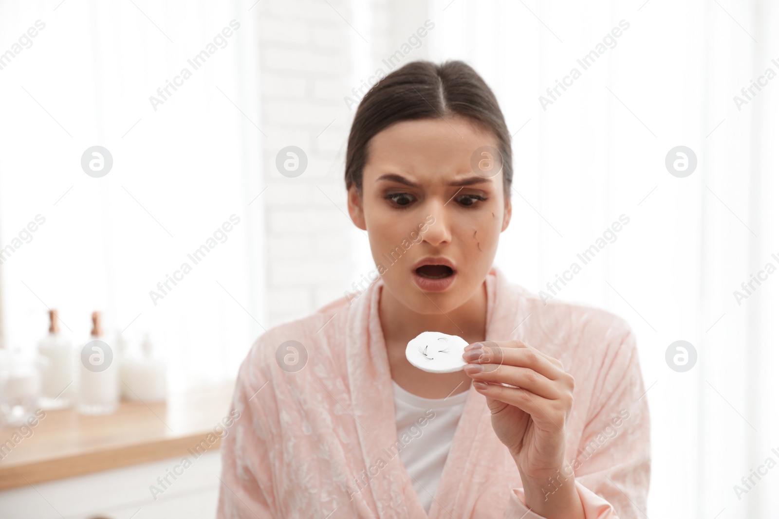 Photo of Beautiful woman holding cotton pad with fallen eyelashes indoors