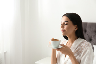 Woman with cup of coffee in bedroom. Lazy morning