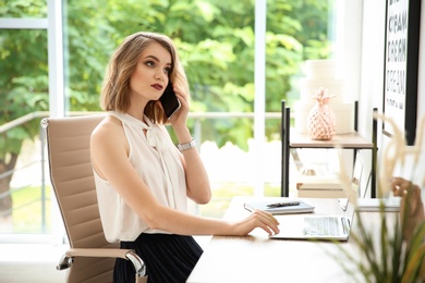 Photo of Young businesswoman talking on phone in office