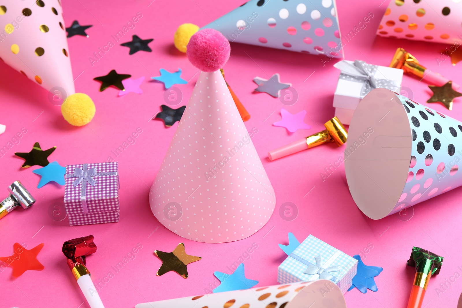 Photo of Party hats and other bright decor elements on pink background