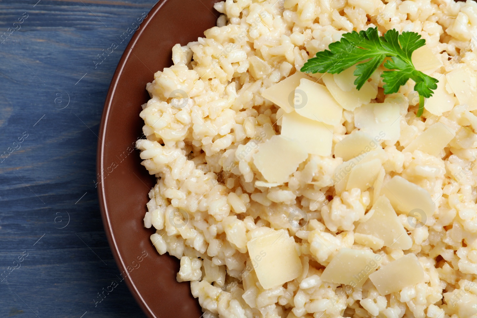 Photo of Delicious risotto with cheese on blue wooden table, closeup