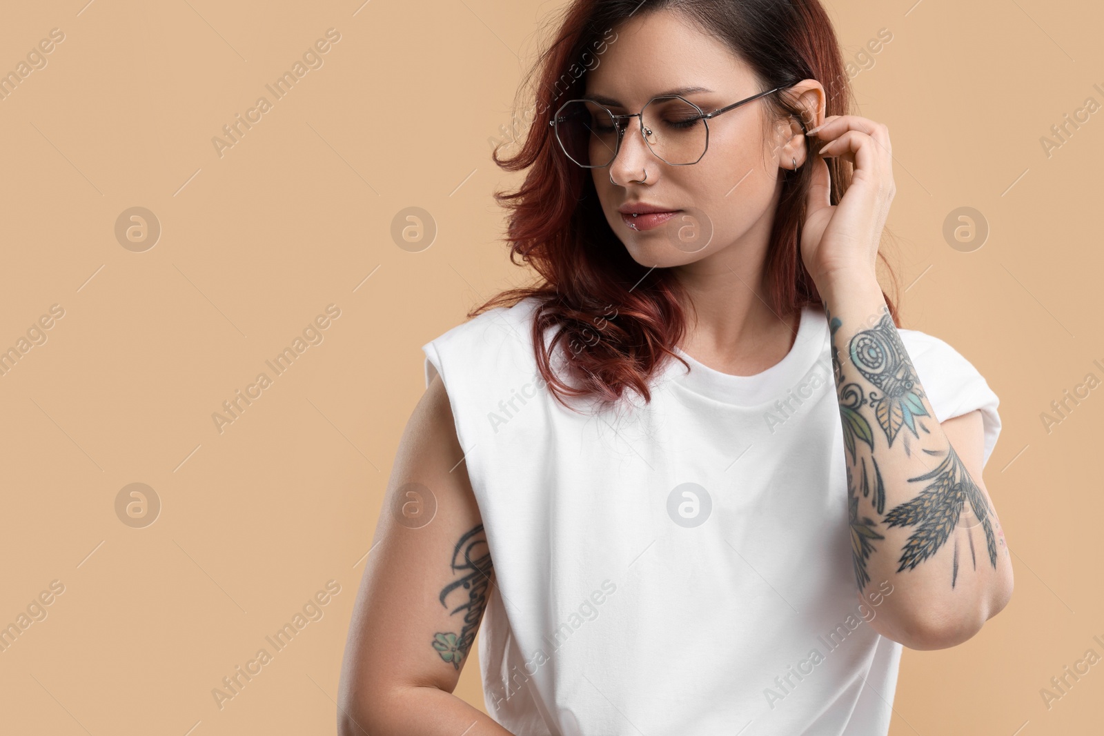 Photo of Beautiful tattooed woman on beige background, space for text